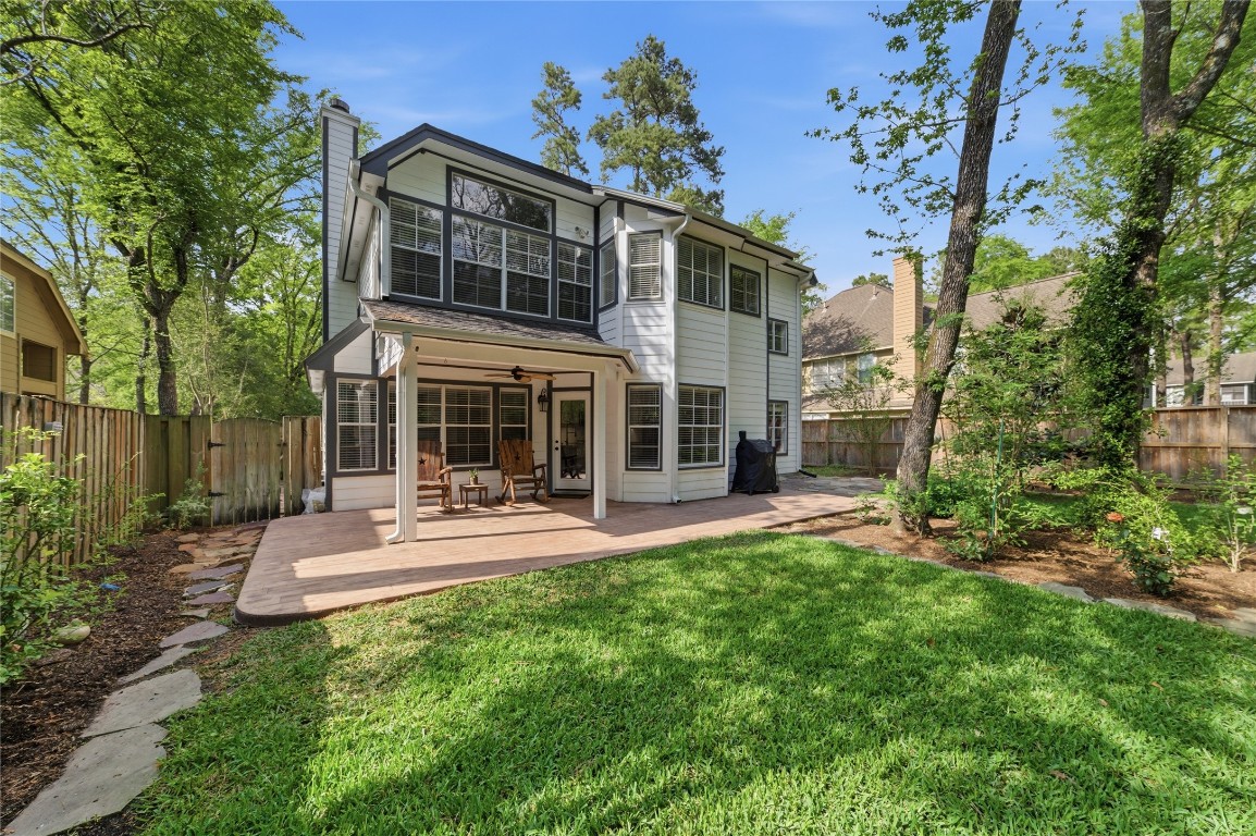 50 East Greywing Circle Spring, TX 77382 - Photo 33 of 37 Spacious backyard featuring a lush lawn, mature trees, and a cozy covered patio, ideal for outdoor relaxation and entertaining.