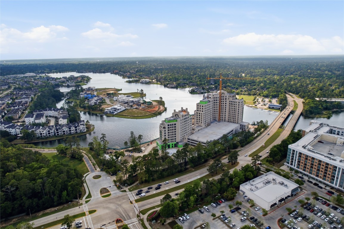 50 East Greywing Circle Spring, TX 77382 - Photo 37 of 37 Scenic lakeside community with modern high-rise buildings, residential homes, and lush greenery. There are well-maintained roads and ample parking, offering convenient access to amenities and picturesque water views, ideal for potential home buyers seeking a vibrant neighborhood.