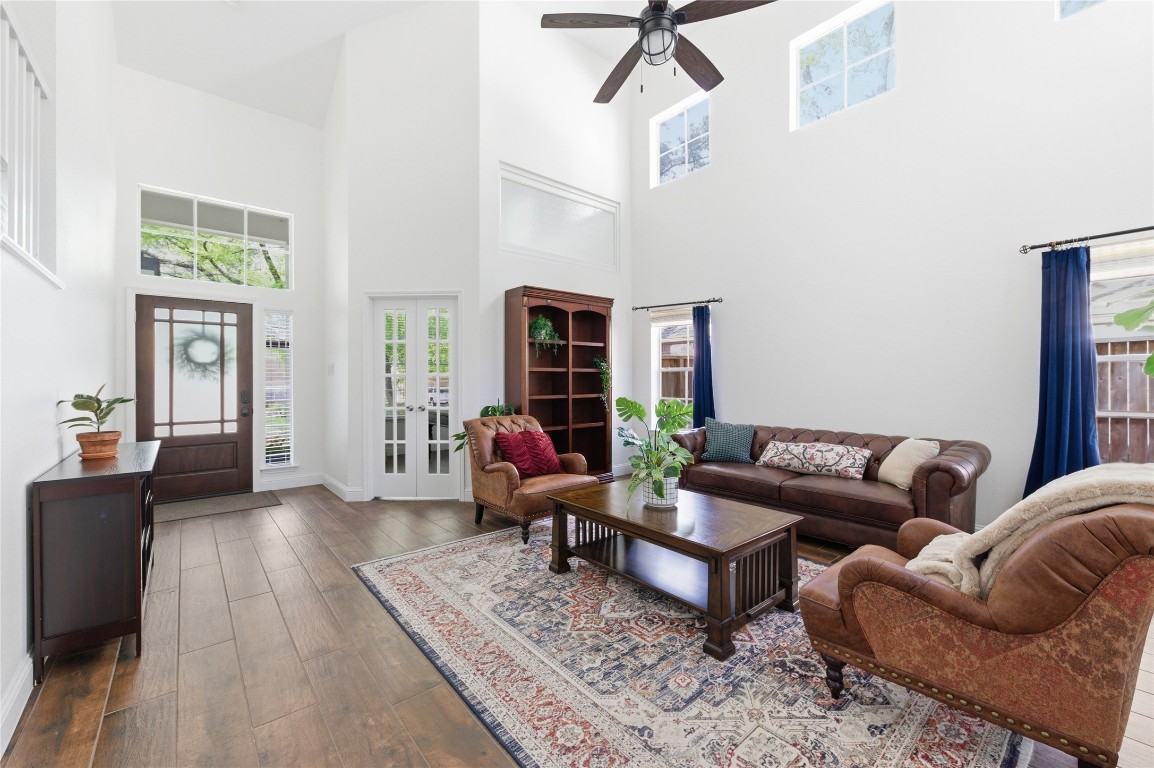 50 East Greywing Circle Spring, TX 77382 - Photo 6 of 37 Bright and spacious living room with high ceilings, large windows, and elegant wood flooring. French doors lead to an adjacent space, enhancing the open feel.