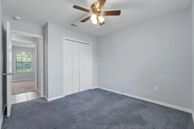 an empty room with a chandelier fan and windows