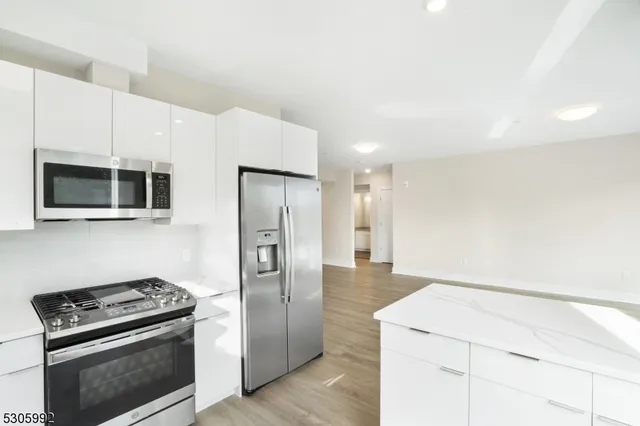 a kitchen with stainless steel appliances a refrigerator a stove top oven and cabinets