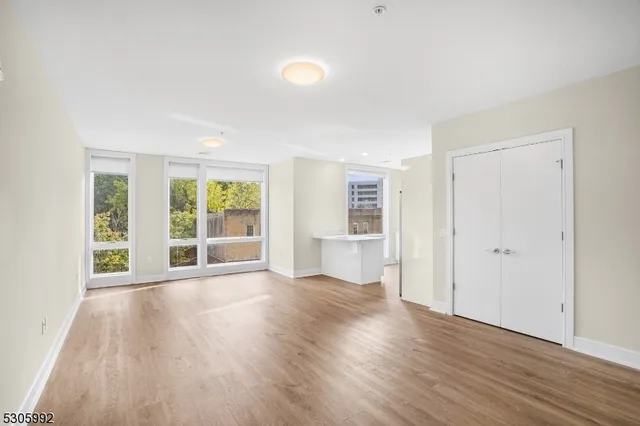 an empty room with wooden floor and windows