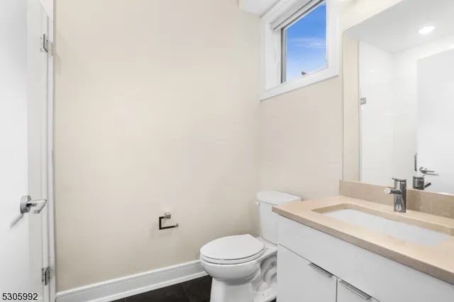 a bathroom with a granite countertop sink a toilet and a mirror