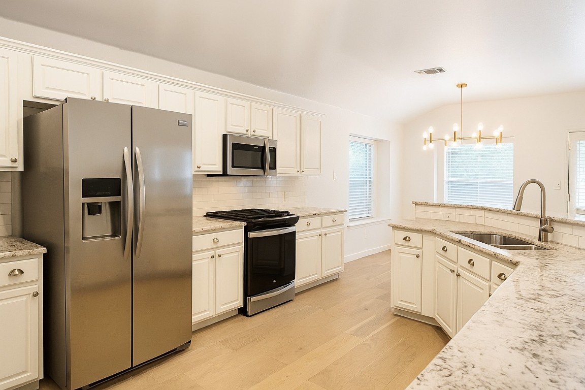 4821 Chesney Ridge Drive Austin, TX 78749 - Photo 5 of 15 a kitchen with stainless steel appliances a refrigerator stove and sink