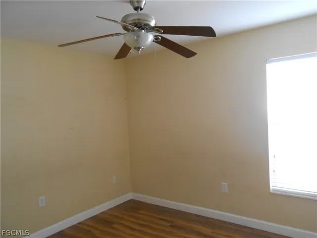 a view of a small space with wooden floor a ceiling fan and window