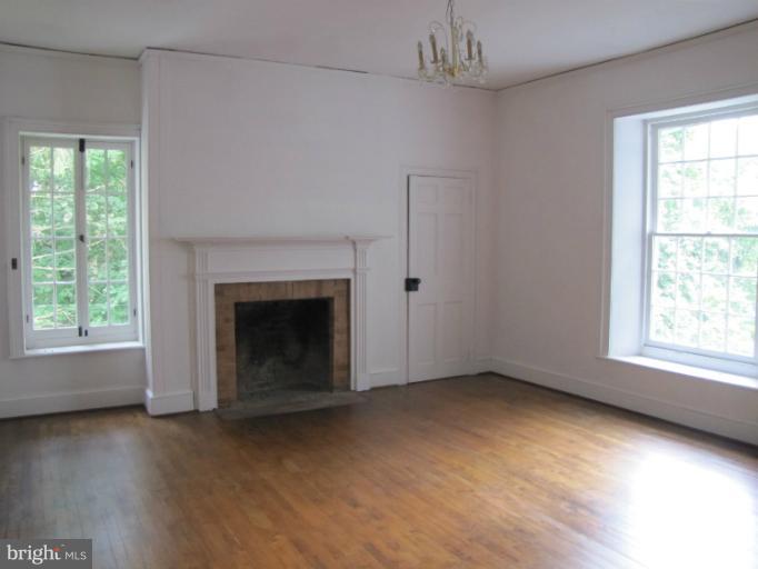 142 Falling Spring Road Shepherdstown, WV 25443 - Photo 22 of 27 an empty room with wooden floor fireplace and windows