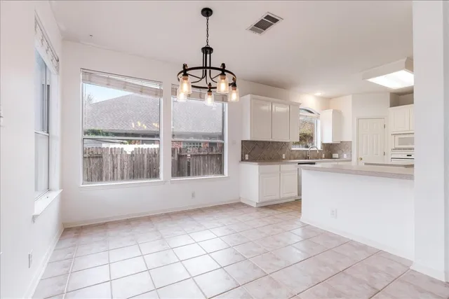 a kitchen with granite countertop a stove a sink and white cabinets