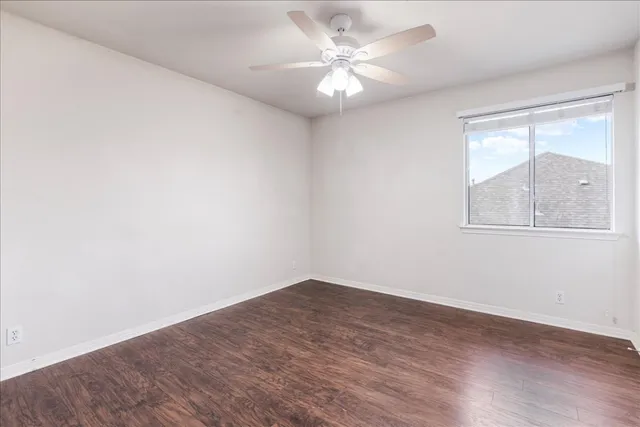 an empty room with wooden floor and fan