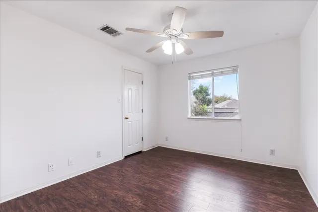a view of a room with wooden floor and a ceiling fan