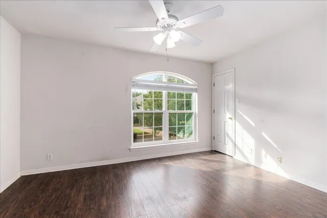 an empty room with wooden floor and ceiling fan