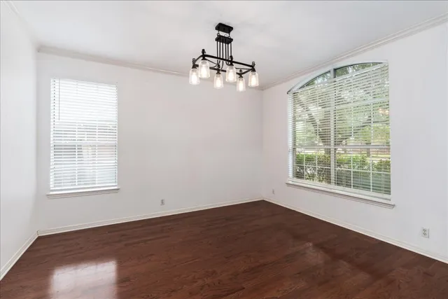 an empty room with wooden floor cabinet and windows