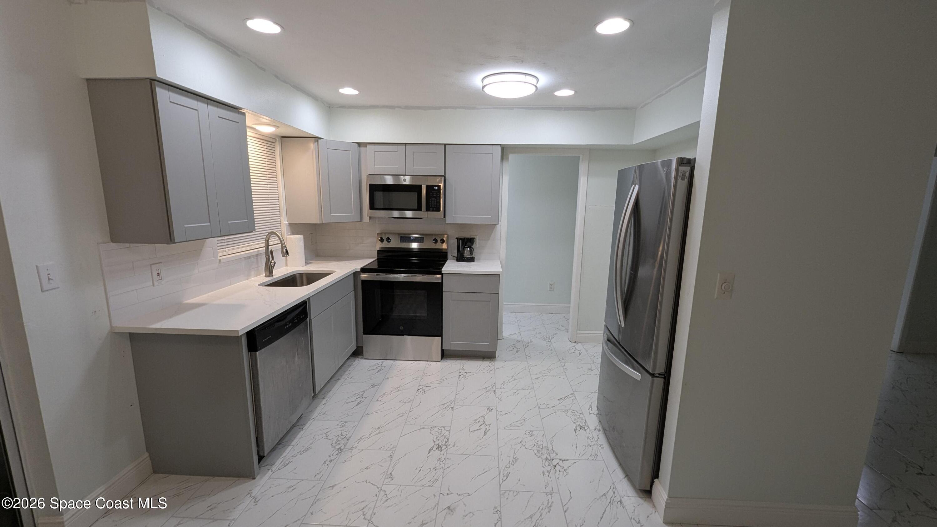 1616 Elizabeth Street Melbourne, FL 32901 - Photo 2 of 14 a kitchen with stainless steel appliances granite countertop a refrigerator a sink a stove a microwave and island