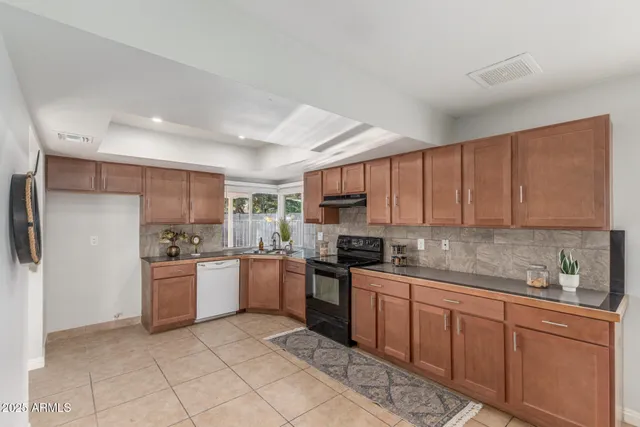 a kitchen with stainless steel appliances granite countertop a stove top oven a sink dishwasher and a refrigerator