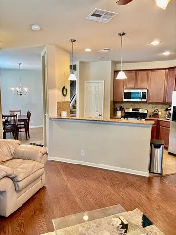 a kitchen with stainless steel appliances kitchen island granite countertop a refrigerator a stove a sink dishwasher and white cabinets with wooden floor