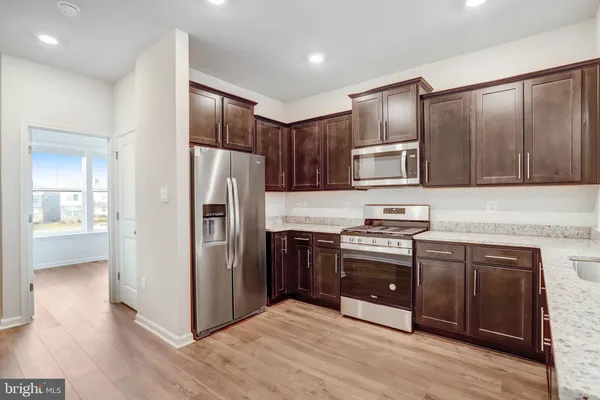 a view of kitchen with stainless steel appliances refrigerator stove microwave and cabinets