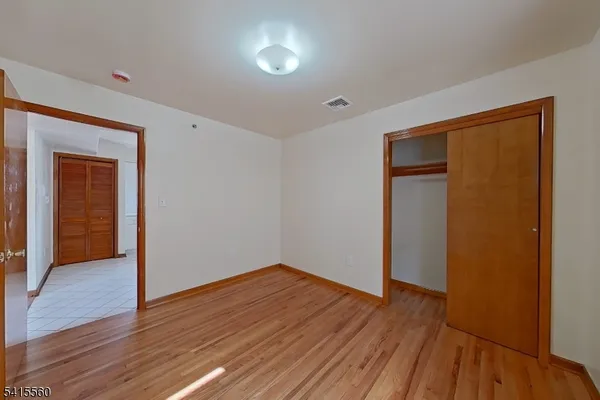 a view of an empty room with wooden floor and closet