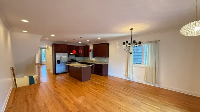 a kitchen with stainless steel appliances kitchen island granite countertop a refrigerator a stove top oven and a sink with granite countertops
