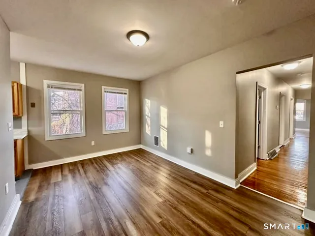 a view of an empty room with window and wooden floor