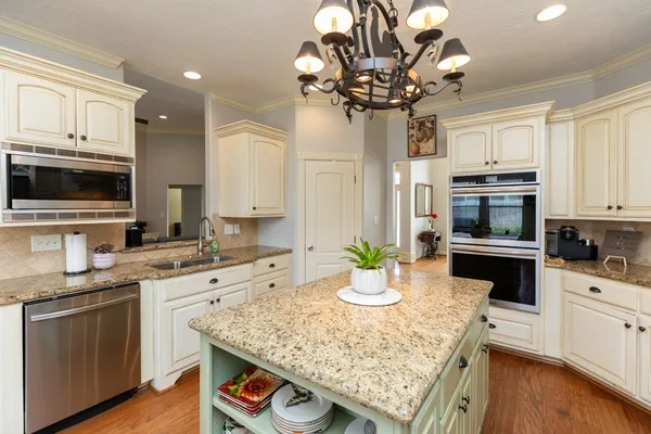 a kitchen with stainless steel appliances granite countertop a sink dishwasher stove and oven with white cabinets