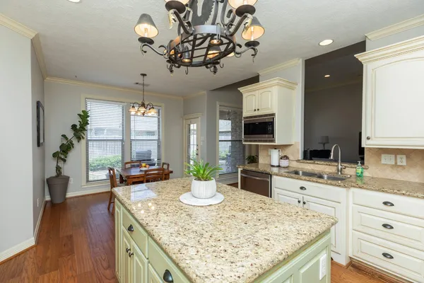 a kitchen with a stove a sink dishwasher and a dining table with wooden floor
