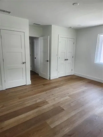 a view of an empty room with wooden floor and window