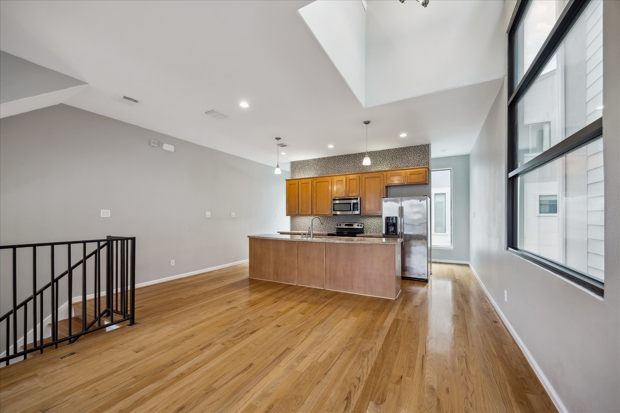 802 Waverly Street, Unit D Houston, TX 77007 - Photo 5 of 30 a large kitchen with stainless steel appliances a large counter top a wooden floor and a large window