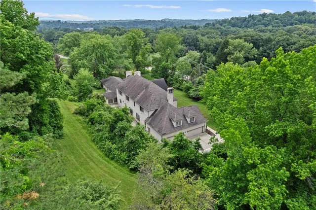 an aerial view of residential house with outdoor space and trees all around