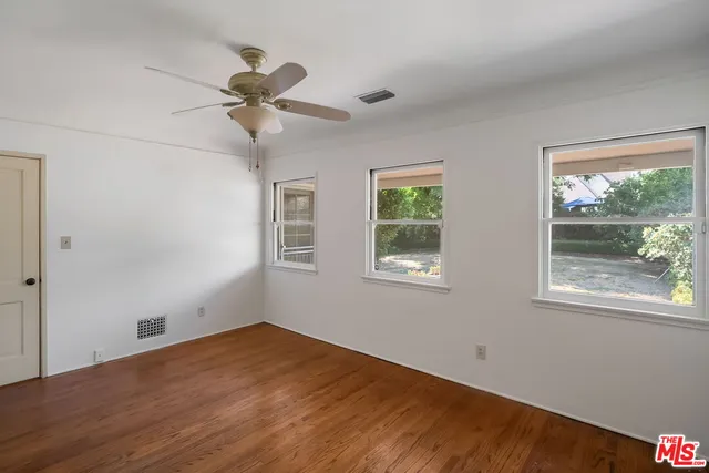 a view of empty room with wooden floor and fan