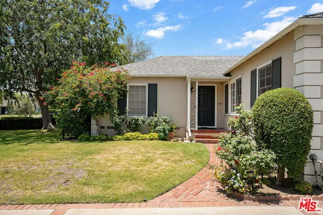 a view of a white house with a yard and potted plants