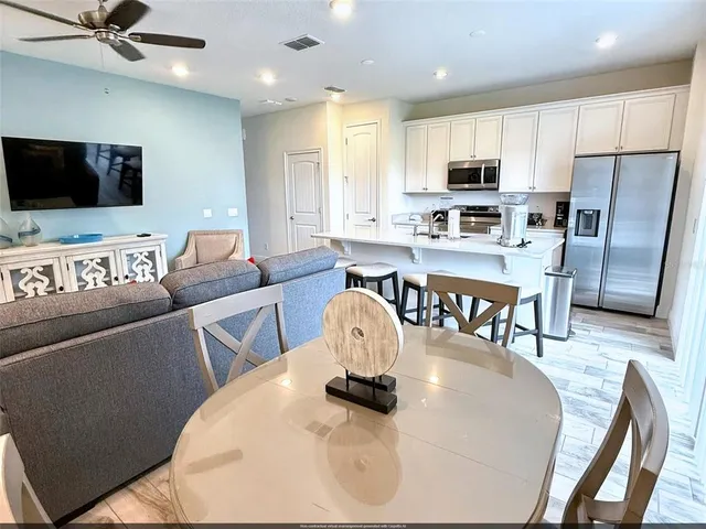 a living room with stainless steel appliances furniture and a flat screen tv