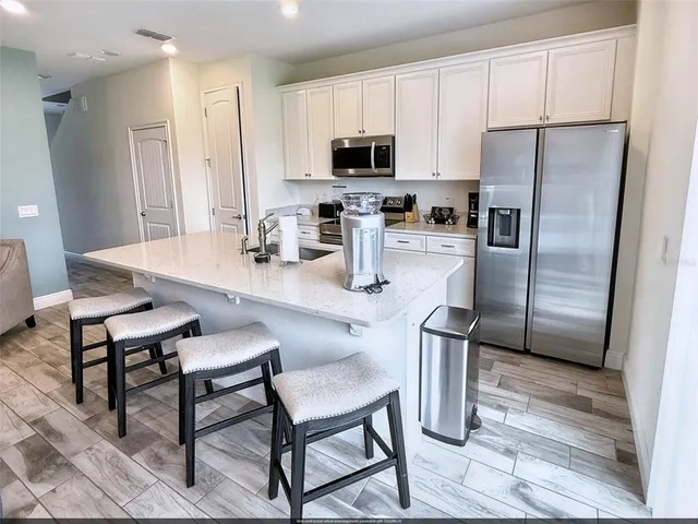 a kitchen with stainless steel appliances granite countertop a refrigerator a stove a sink a dining table and chairs