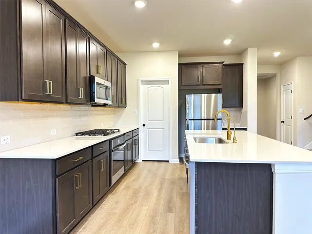 a large kitchen with stainless steel appliances granite countertop a lot of counter space and wooden floor