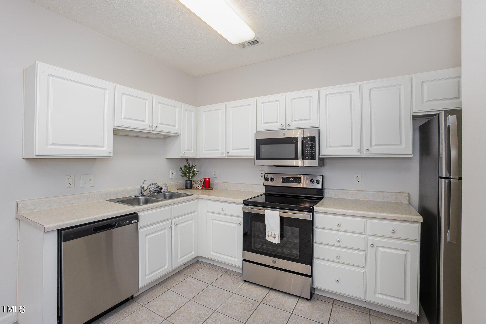 2500 Friedland Place, Unit 302 Raleigh, NC 27617 - Photo 5 of 15 a kitchen with white cabinets stainless steel appliances and sink