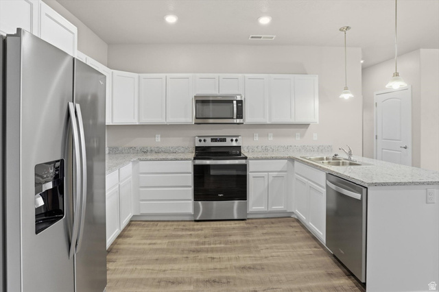 1838 West 300th Street South, Unit B Mapleton, UT 84664 - Photo 14 of 51 Modern kitchen featuring white cabinetry, light-toned granite-style countertops, stainless steel appliances, wood-finish flooring, and pendant lighting over the island