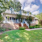 a front view of a house with garden and trees