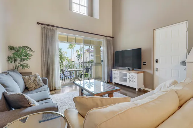 a living room with furniture a flat screen tv and a floor to ceiling window