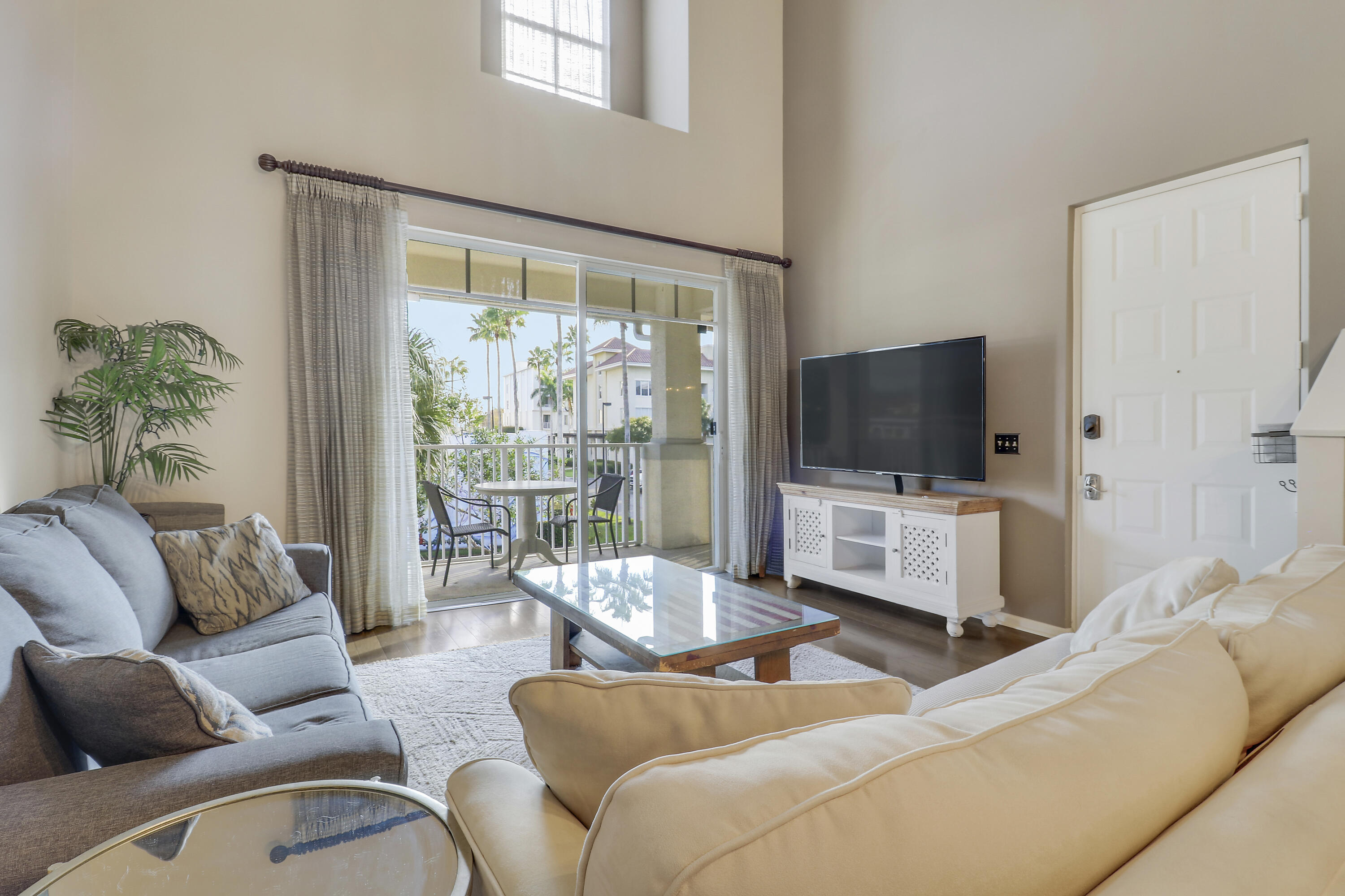 1152 University Boulevard, Unit 22 Jupiter, FL 33458 - Photo 3 of 24 a living room with furniture a flat screen tv and a floor to ceiling window