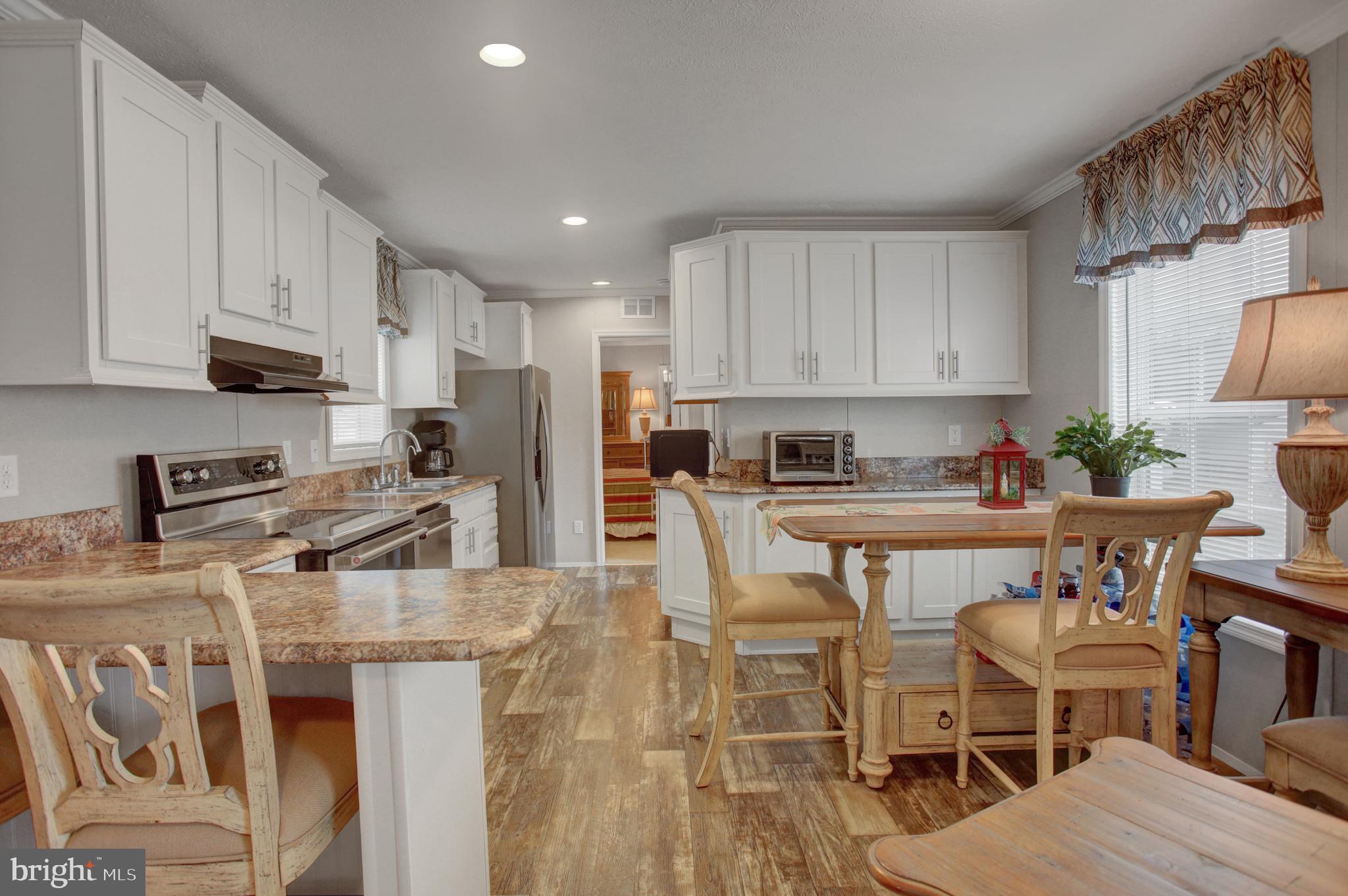 113 Big Spring Terrace Newville, PA 17241 - Photo 7 of 37 a kitchen with stainless steel appliances granite countertop a stove top oven a sink a refrigerator white cabinets and chairs with wooden floor