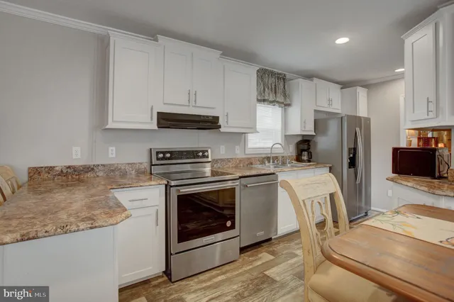 a kitchen with stainless steel appliances granite countertop a stove a refrigerator a sink a microwave and white cabinets