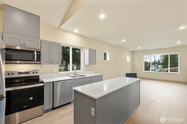 a large kitchen with stainless steel appliances a stove a sink a microwave and a refrigerator