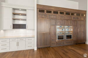 1141 East Lost Ridge Drive Washington, UT 84780 - Photo 35 of 108 Expansive kitchen wall featuring integrated ovens, custom cabinetry, wood-finish flooring, recessed lighting, and a white subway tile backsplash