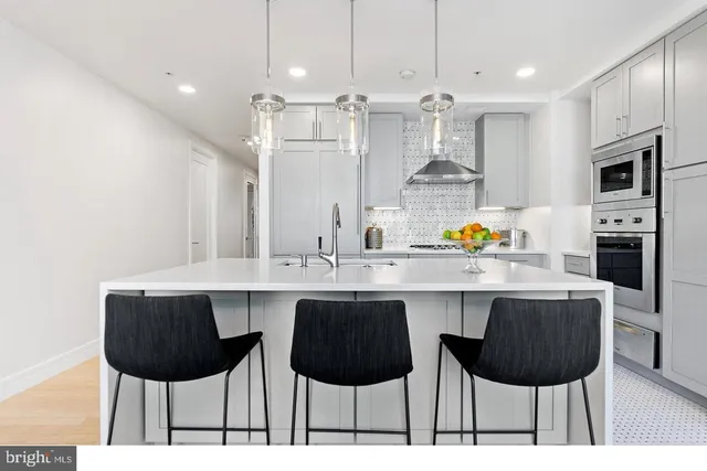 a kitchen with stainless steel appliances a kitchen island a stove a kitchen island and chairs in it