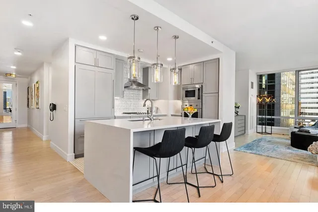 a kitchen with stainless steel appliances kitchen island granite countertop a dining table chairs and white cabinets