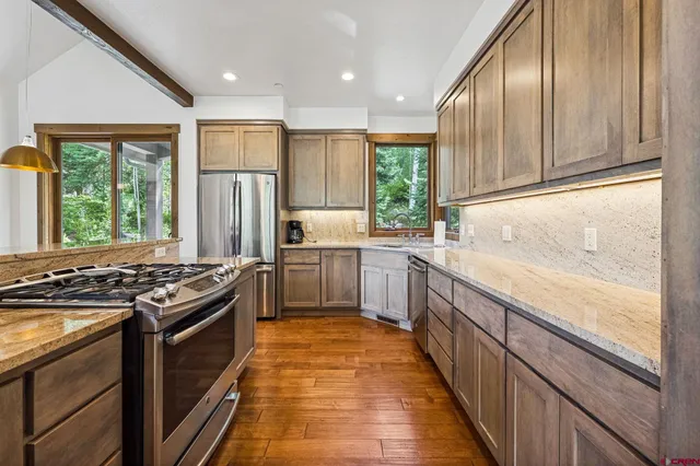 a kitchen with stainless steel appliances granite countertop a stove a sink and a refrigerator