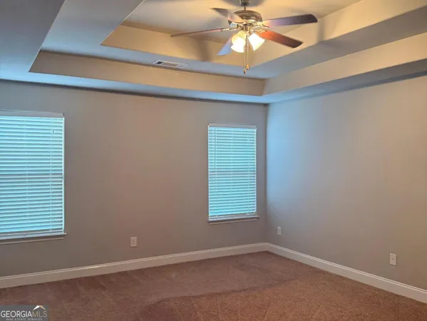 an empty room with windows and fan