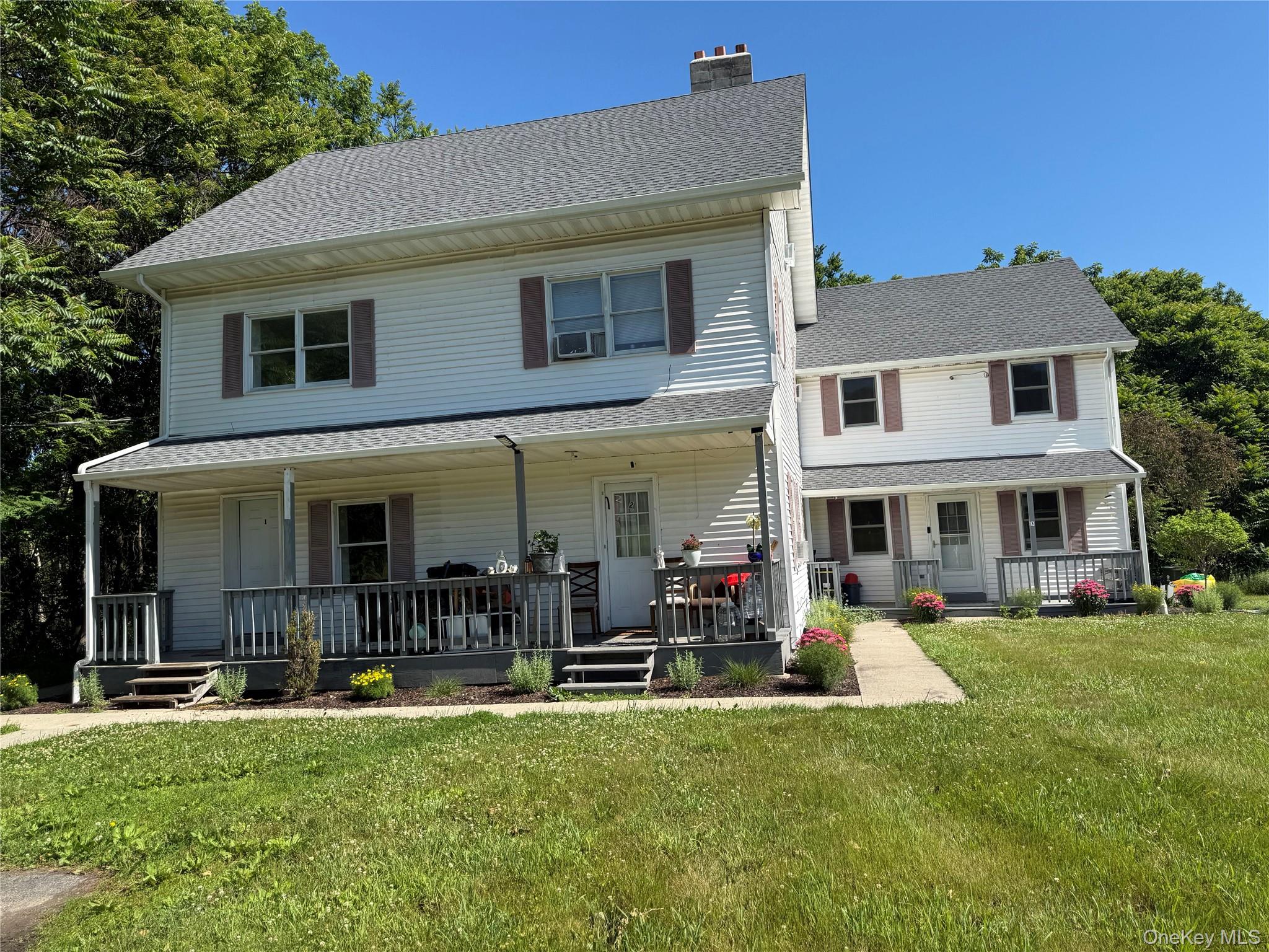 A covered front porch , white siding exterior with brown shutters