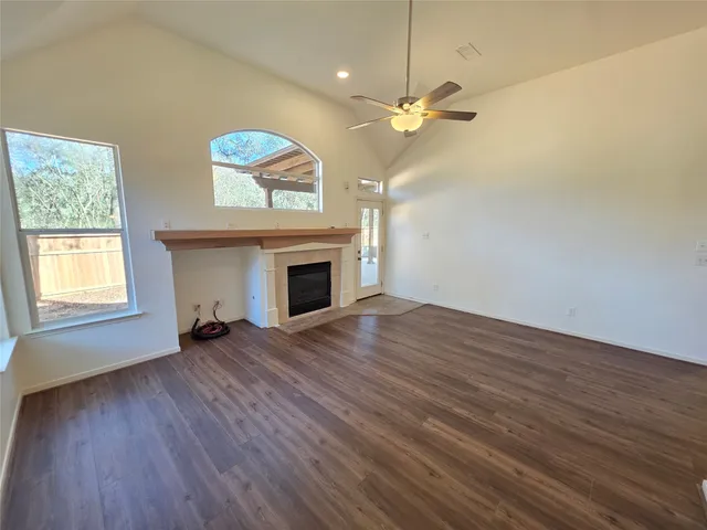 an empty room with wooden floor fireplace and windows