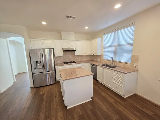 a kitchen with a refrigerator a stove top oven and wooden floor