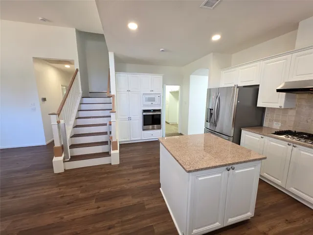 a kitchen with stainless steel appliances granite countertop a refrigerator a stove a sink and a refrigerator