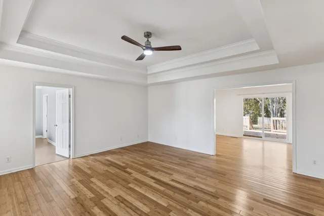 a view of empty room with wooden floor and ceiling fan